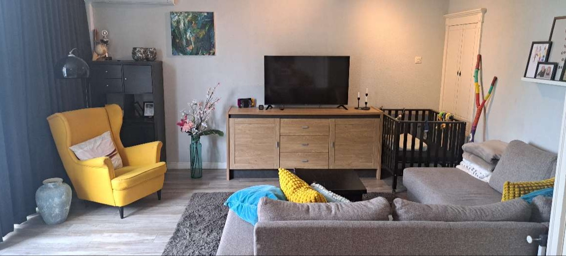 Woonkamer met zithoek en babybox